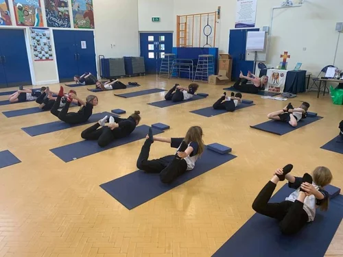 Primary school pupils doing partner yoga and balance work in Wigan